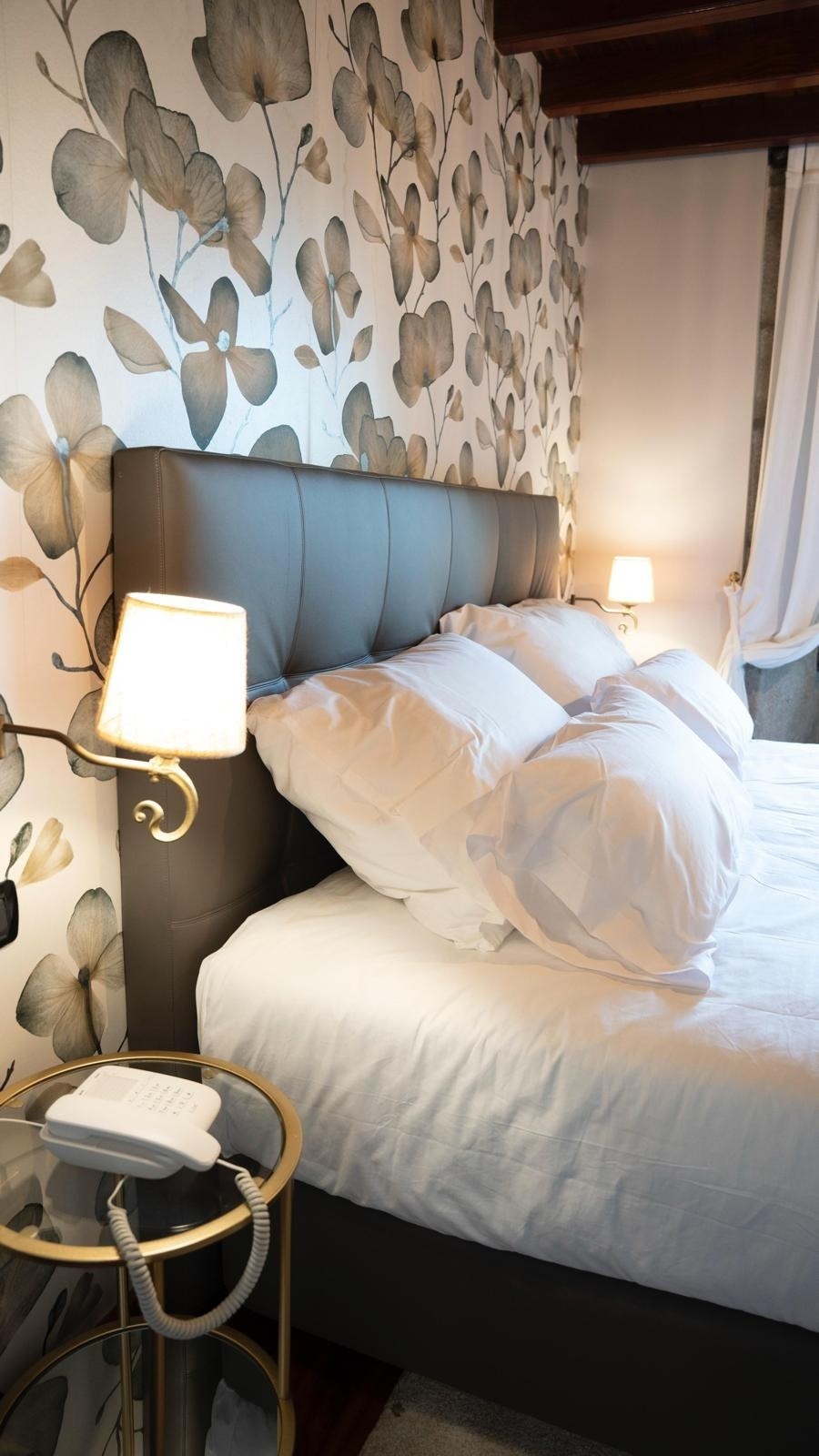 una cama con una lámpara y un teléfono en la mesita de noche