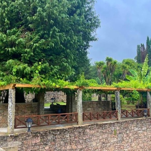 un patio de piedra con una pérgola y un árbol en el fondo