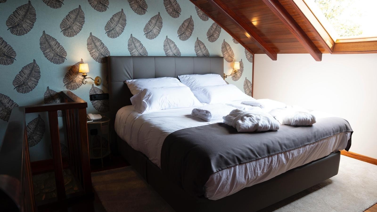 una habitación con una cama y una pared con hojas