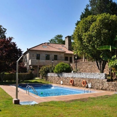 Pazo de Adran SNO: Relájate en la piscina con vistas a la casa y un jardín frondoso.