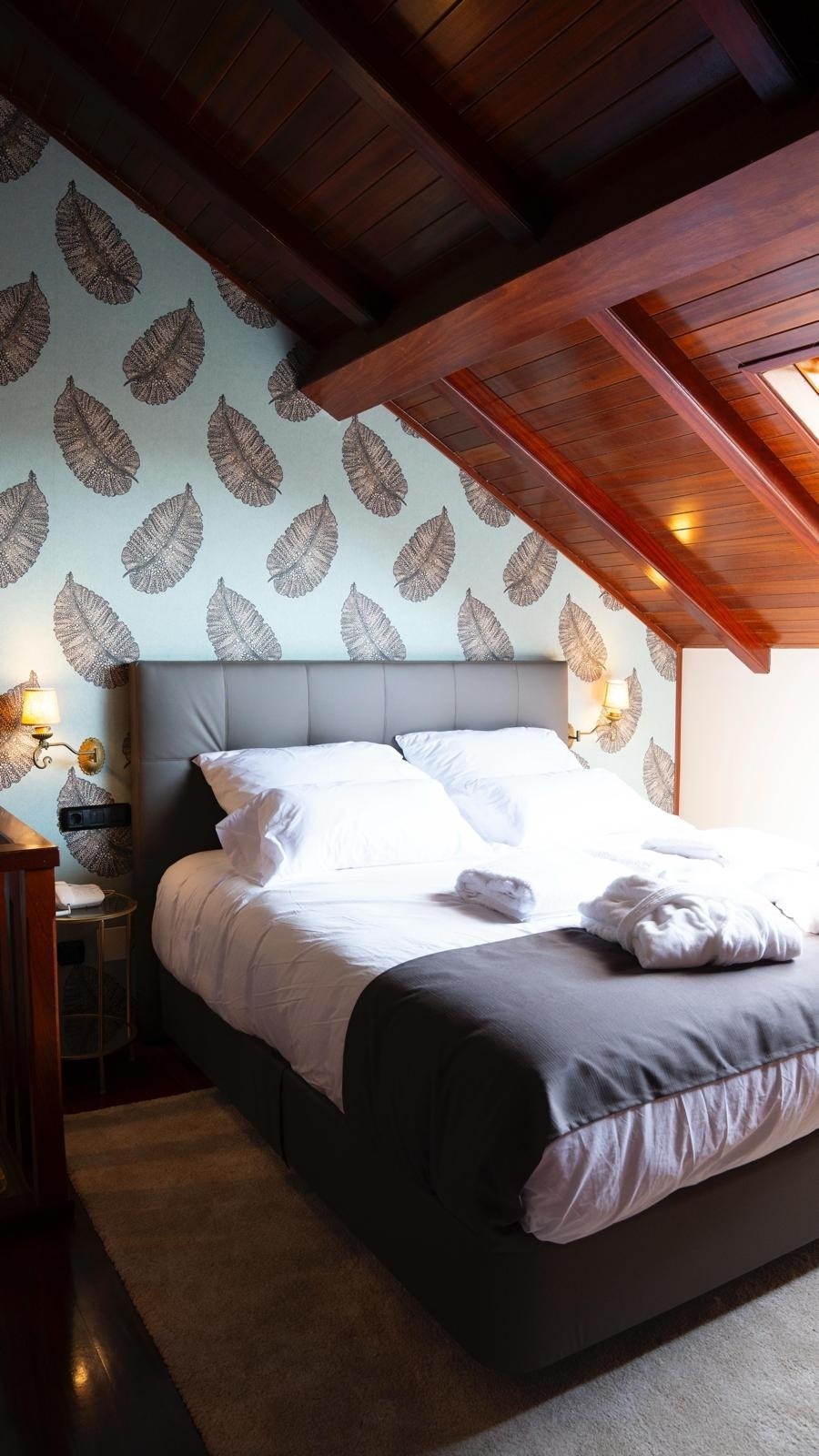 una habitación con una cama y un papel pintado de hojas