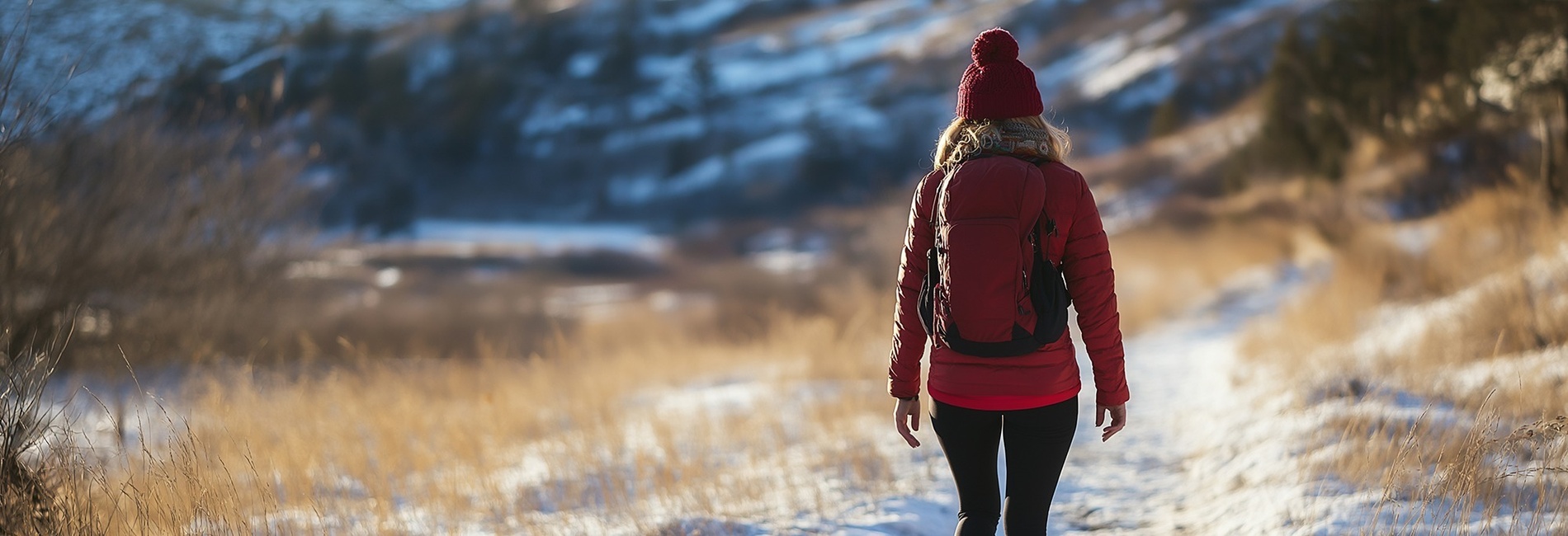 une femme portant un chapeau rouge et une veste rouge marche dans la neige