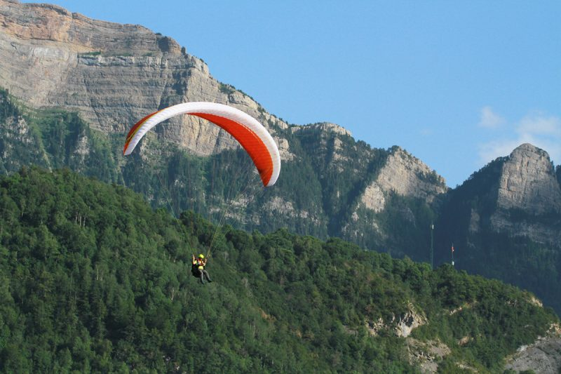 un parapente rojo y blanco está volando sobre una montaña