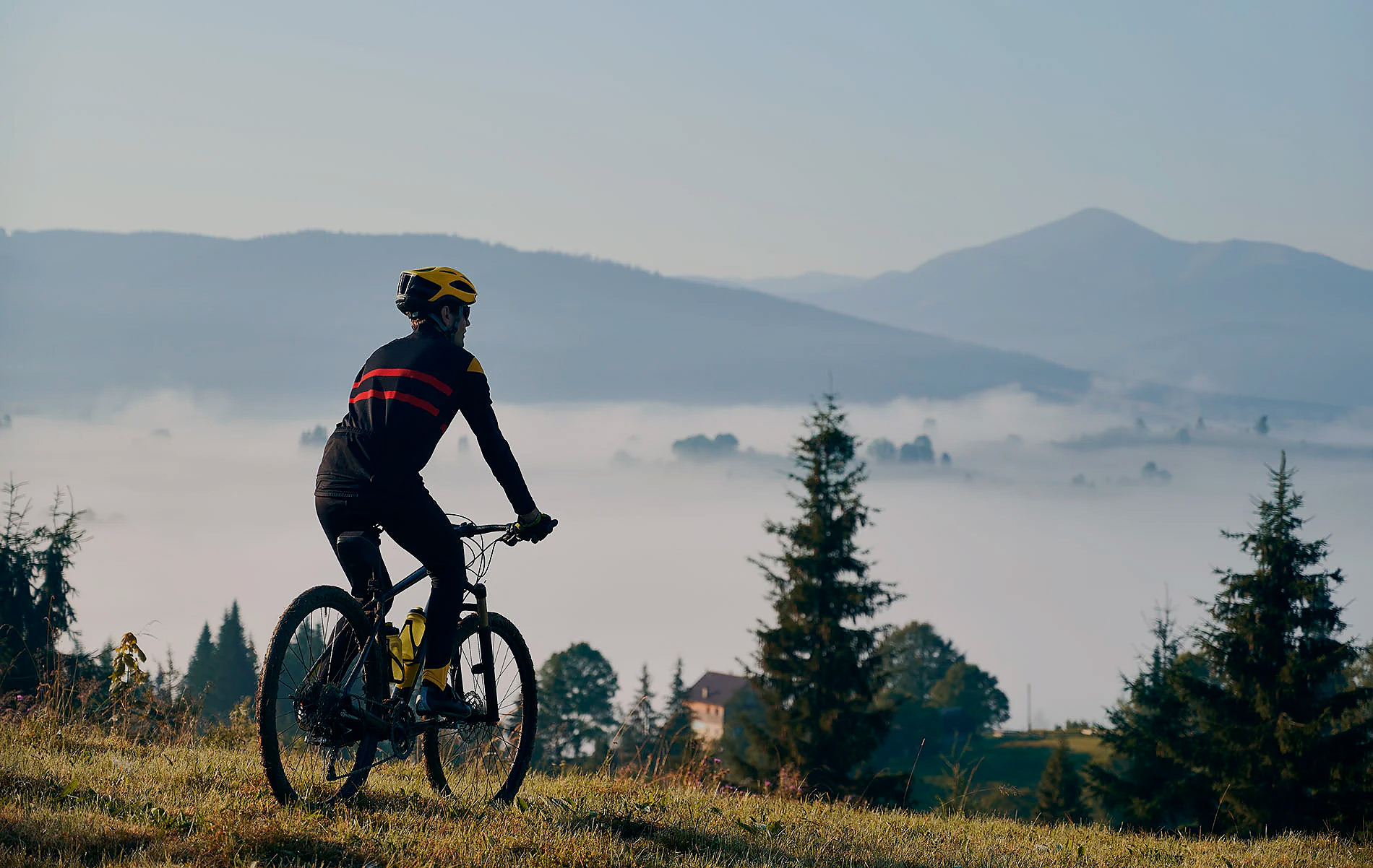 Cycliste dans les montagnes brumeuses au lever du soleil, une belle évasion pour SNO: Aragon Hills.