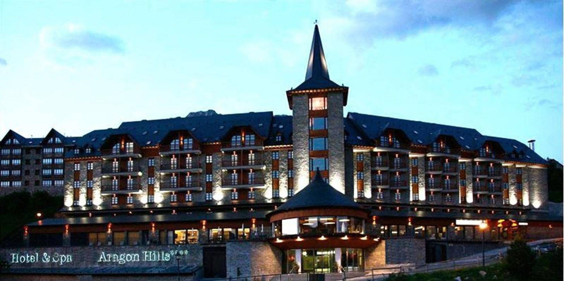 Hotel & Spa Aragon Hills, edificio con torre iluminado al anochecer.