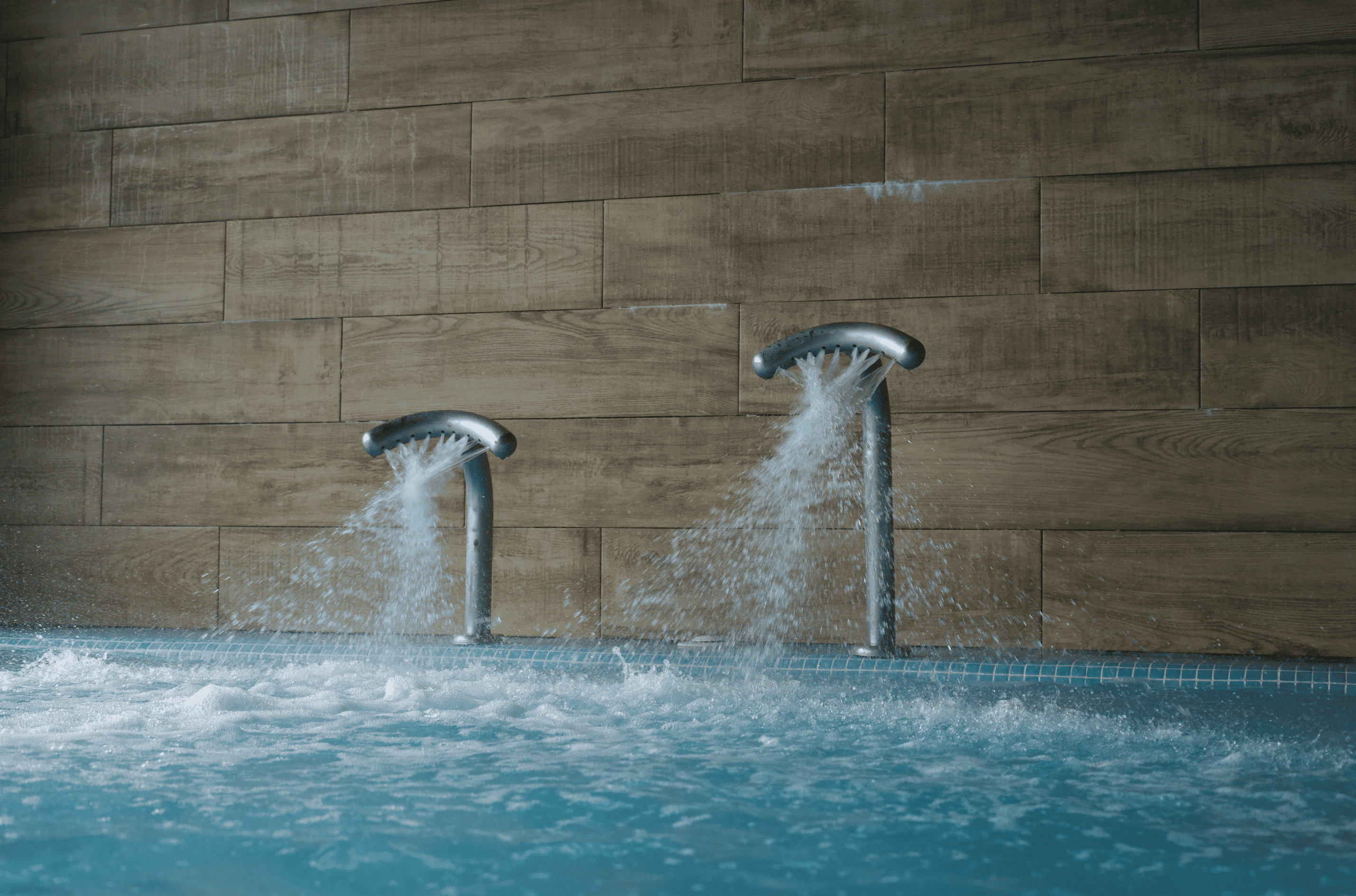 Piscina de spa con chorros de agua y pared de azulejos efecto madera.