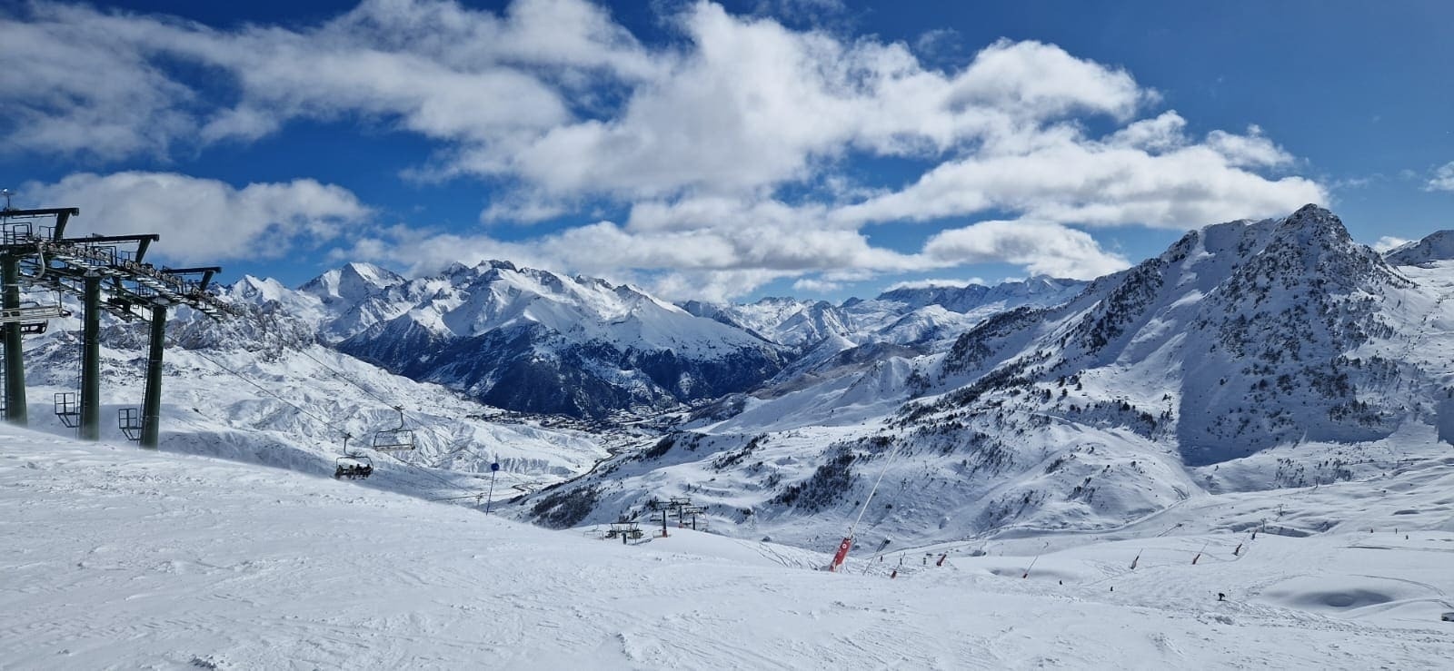 a snowy mountain range with a few trees in the foreground
