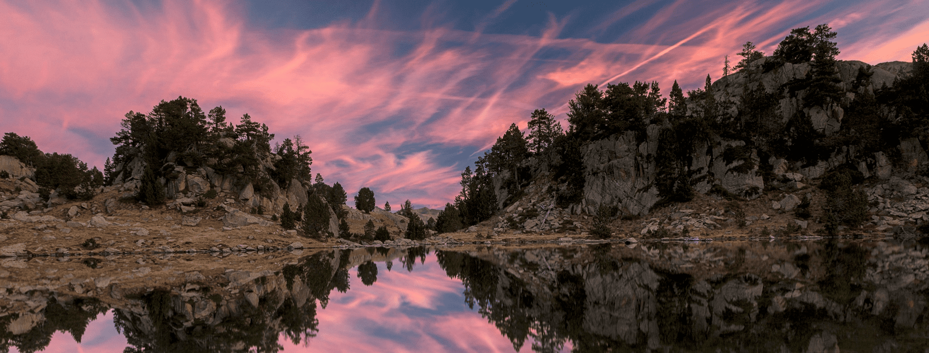 a sunset over a lake with trees in the background