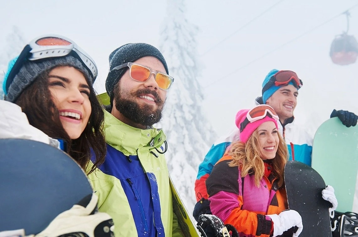 un grupo de snowboarders sonríe mientras sostienen sus tablas de snowboard