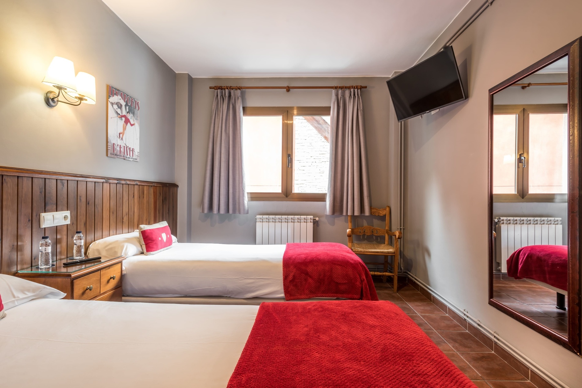 Chambre double hôtel SNO: Beret, lits jumeaux et plaids rouges.