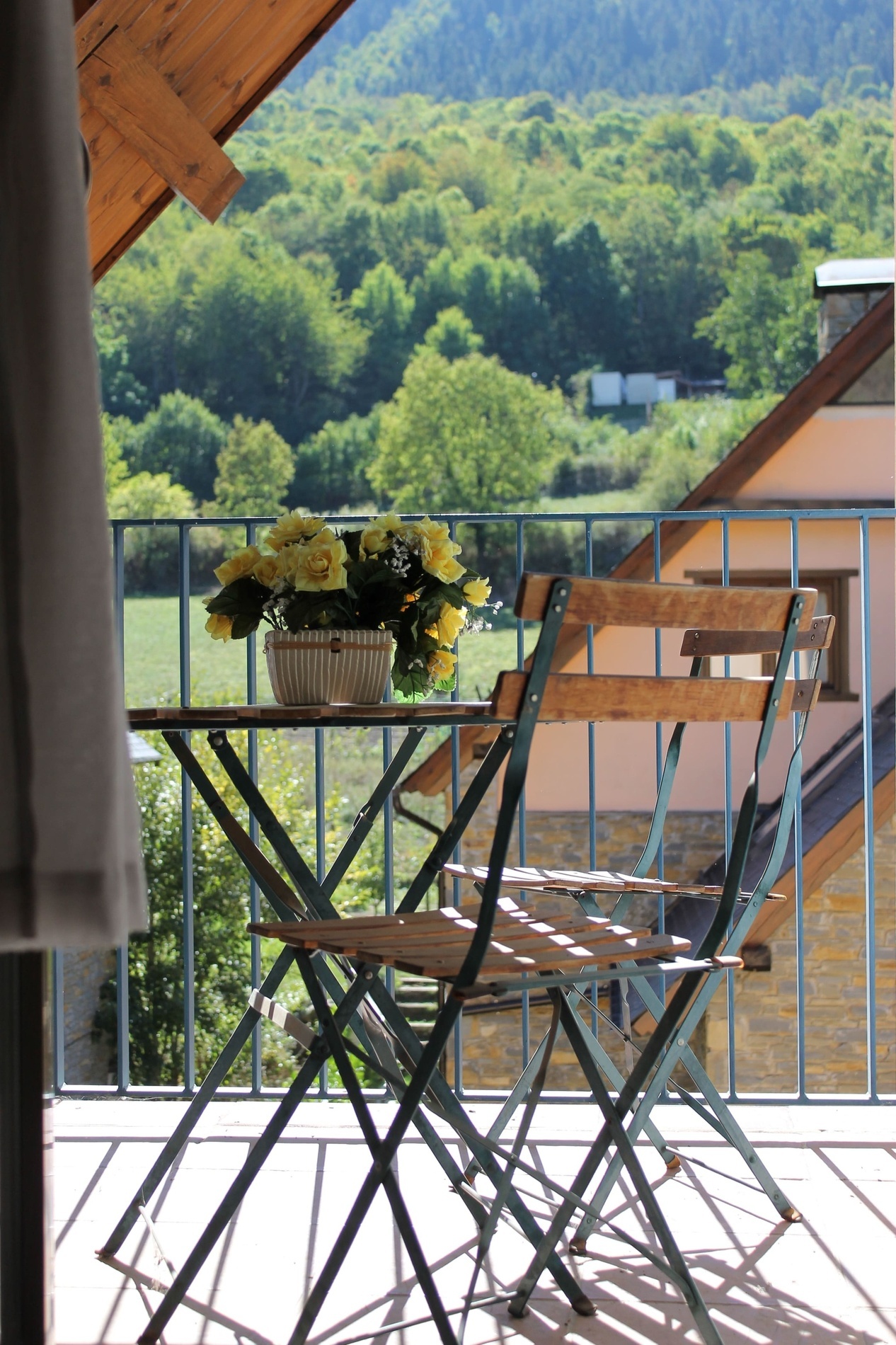 une table et des chaises sur un balcon avec un pot de fleurs sur la table