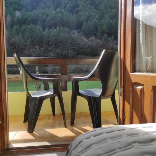 dos sillas y una mesa en un balcón con una vista del bosque