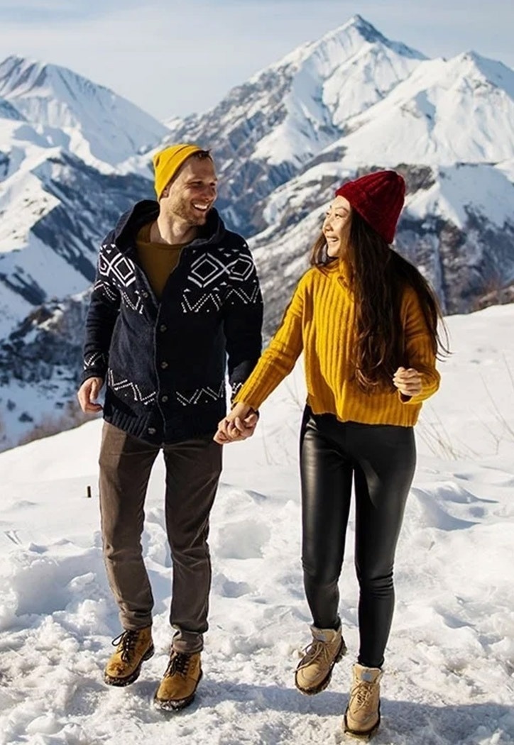 un homme et une femme se tiennent la main en marchant dans la neige