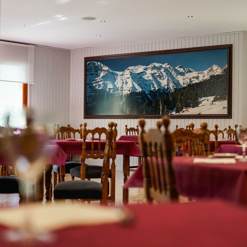 un restaurante con mesas y sillas y una pintura de montañas en la pared