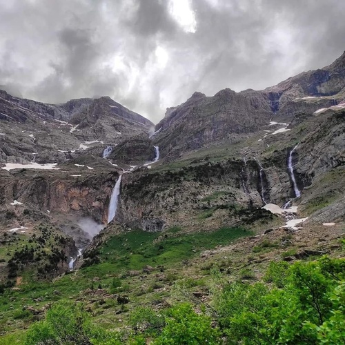 deux chutes d' eau dans une vallée de montagne sous un ciel nuageux