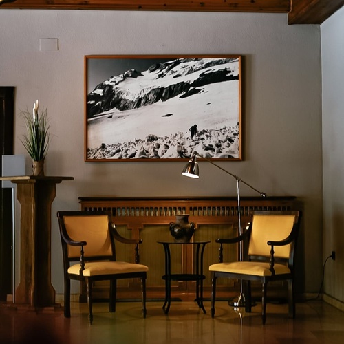 une peinture d' une montagne est accrochée au mur à côté de deux chaises jaunes