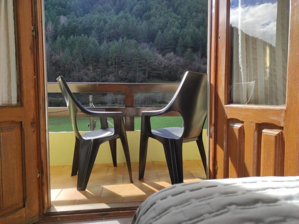 two chairs and a table on a balcony overlooking a forest