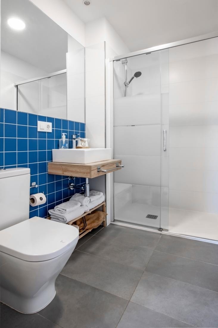 un baño con azulejos azules y un inodoro blanco