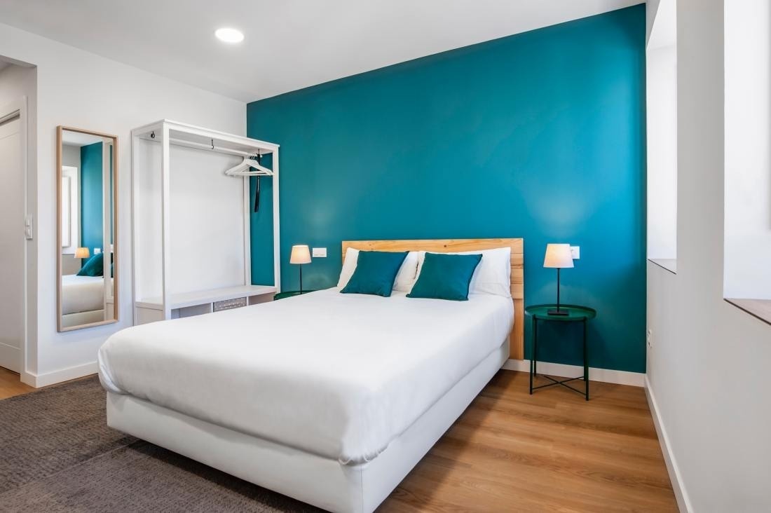 una habitación con una cama blanca y una pared azul