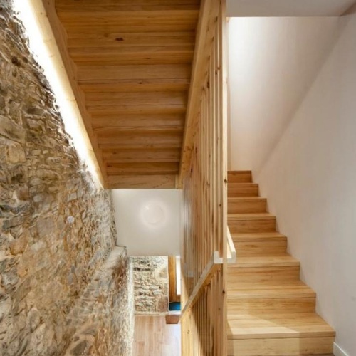 una escalera de madera con una pared de piedra al fondo