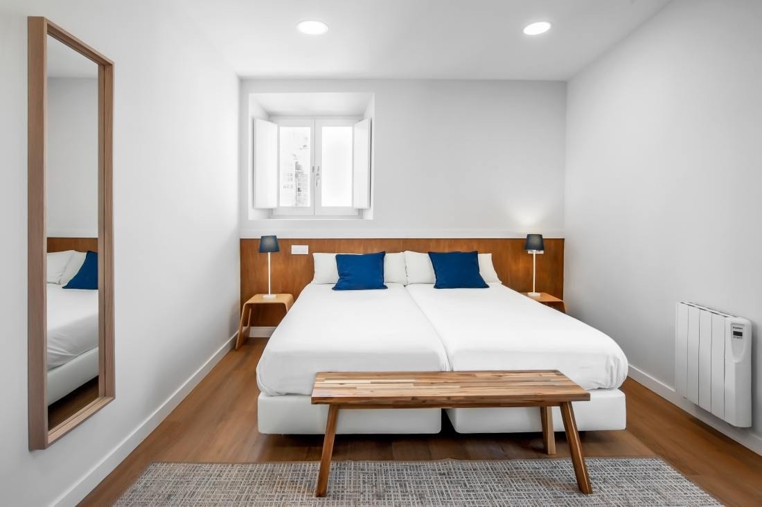 un dormitorio pequeño con una cama blanca y almohadas azules