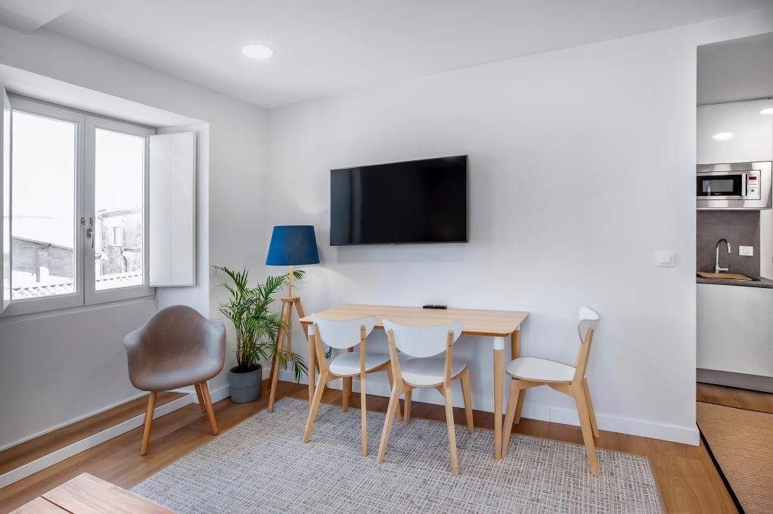 una habitación con una mesa y sillas y una televisión en la pared