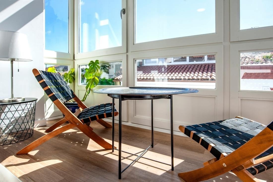 dos sillas de madera y una mesa frente a una ventana