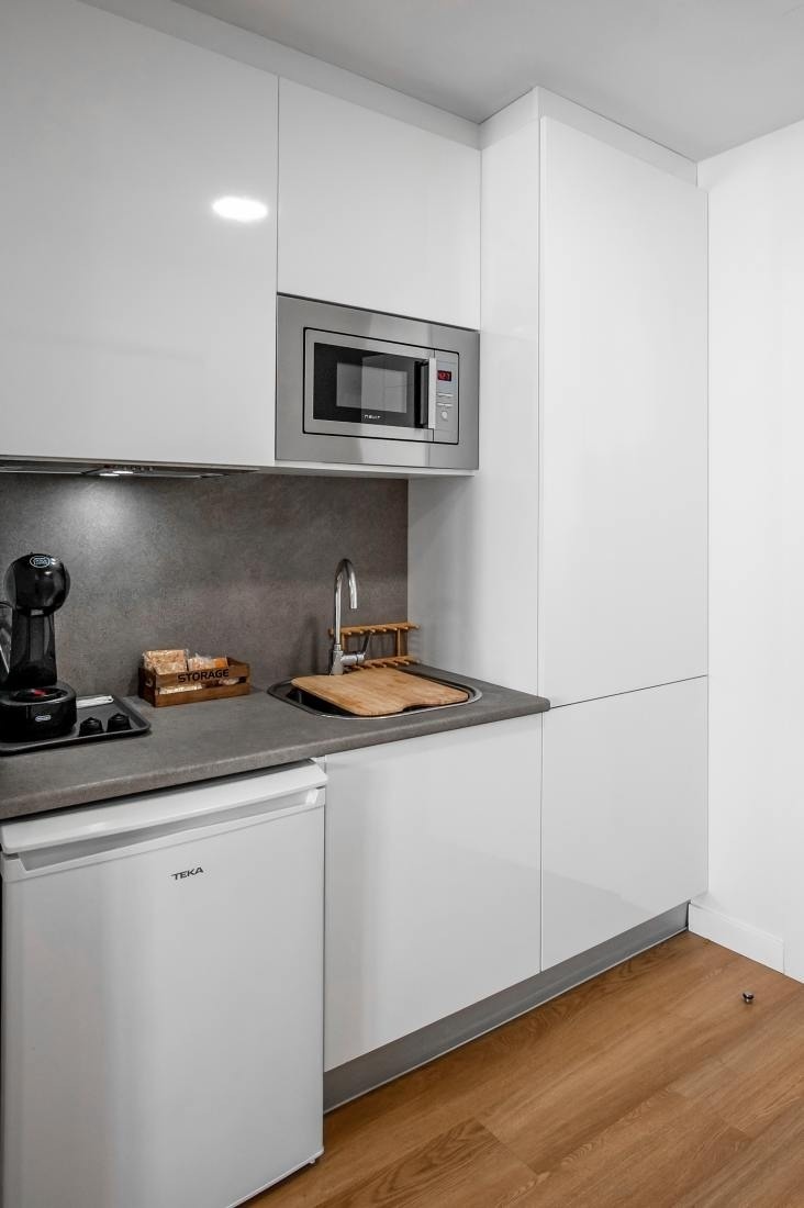 una cocina pequeña con gabinetes blancos y electrodomésticos teco