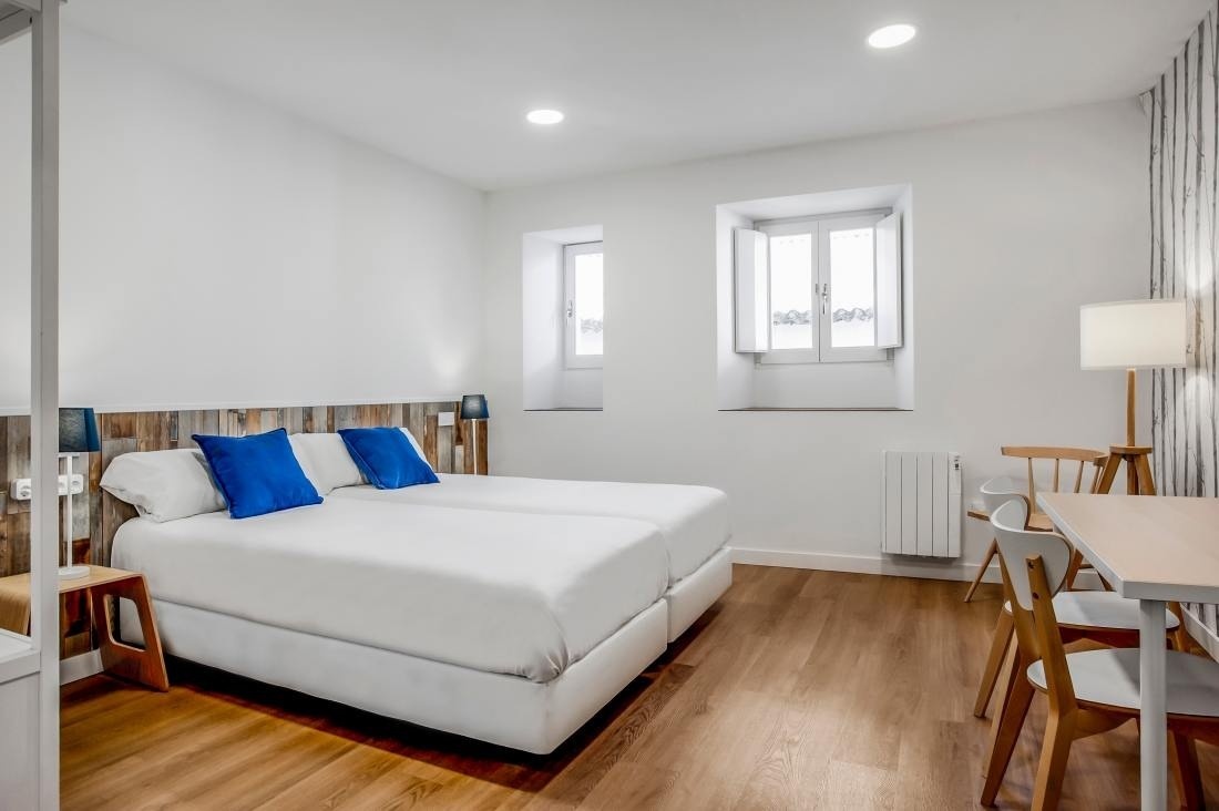 una habitación con dos camas blancas y almohadas azules