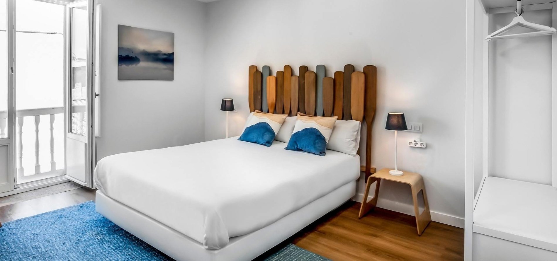 una habitación con una cama blanca y una cabecera de madera