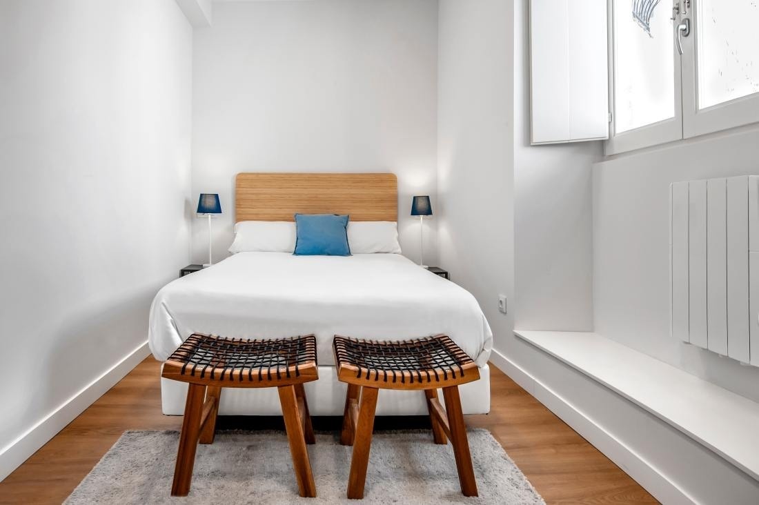 un dormitorio pequeño con una cama y dos taburetes