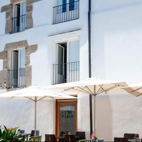 un patio con mesas y sombrillas frente a un edificio blanco