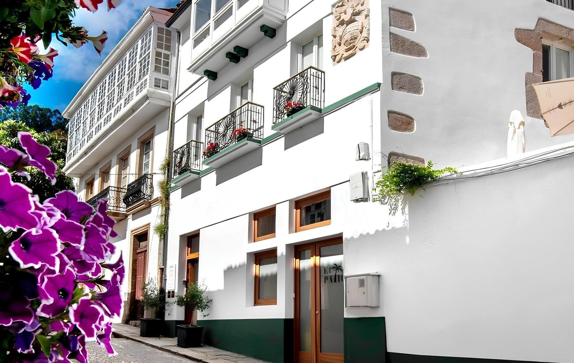 un edificio blanco con balcones y flores moradas