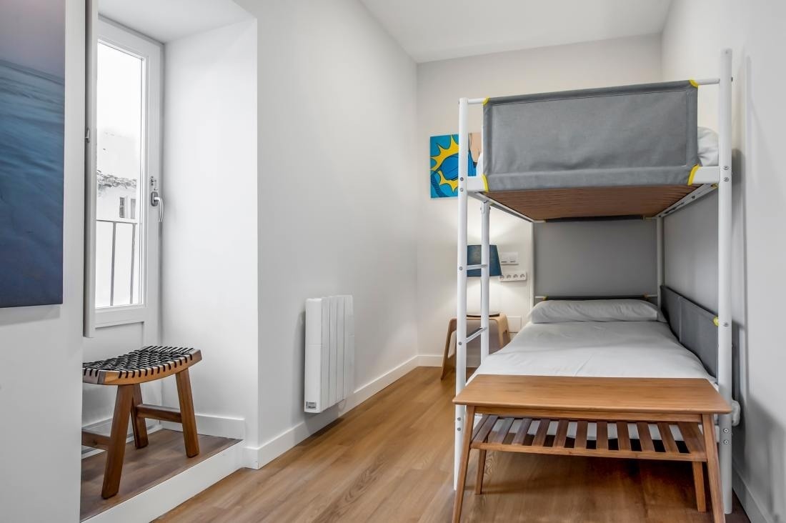 una habitación con dos literas y un taburete de madera