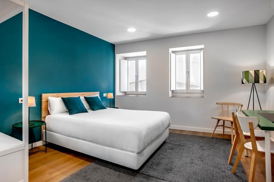 una habitación con una cama blanca y una pared azul