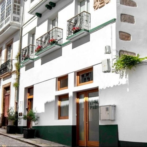 un edificio blanco con balcones y flores moradas en el primer plano