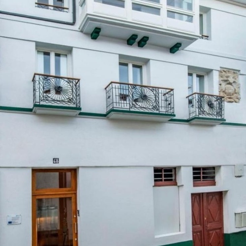 un edificio blanco con balcones verdes y la puerta de madera