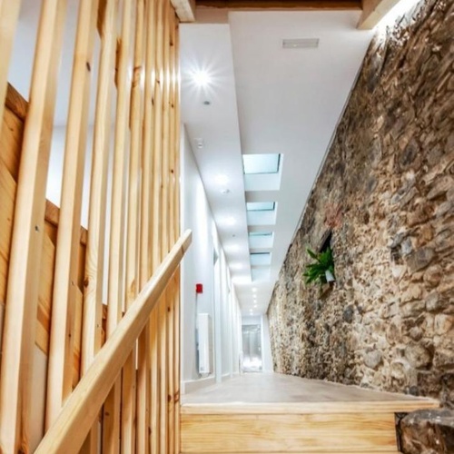 un pasillo con escaleras de madera y una pared de piedra