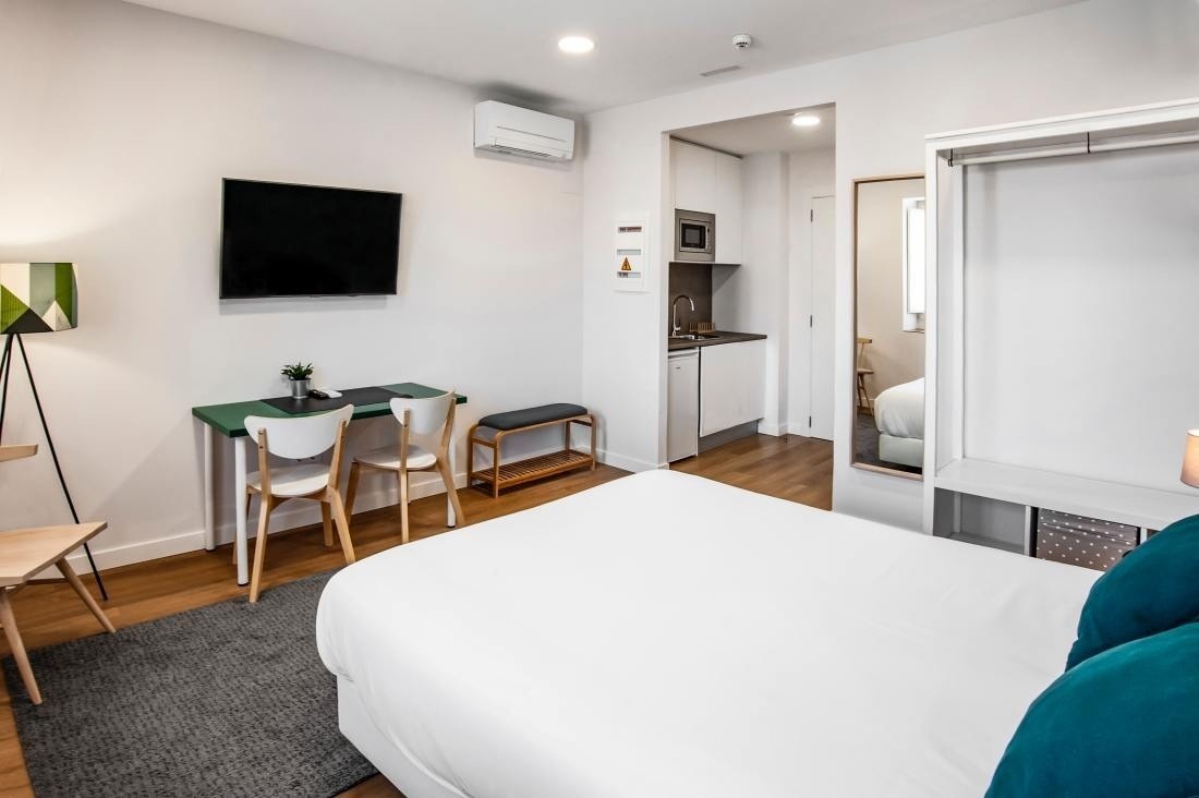 una habitación con una cama y una televisión en la pared