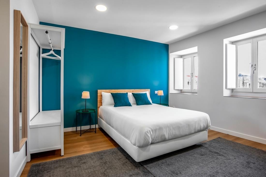 una habitación con una cama blanca y una pared azul