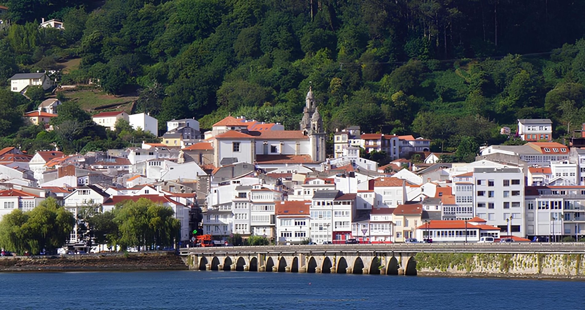 un pequeño pueblo junto a un río con edificios blancos y techos rojos