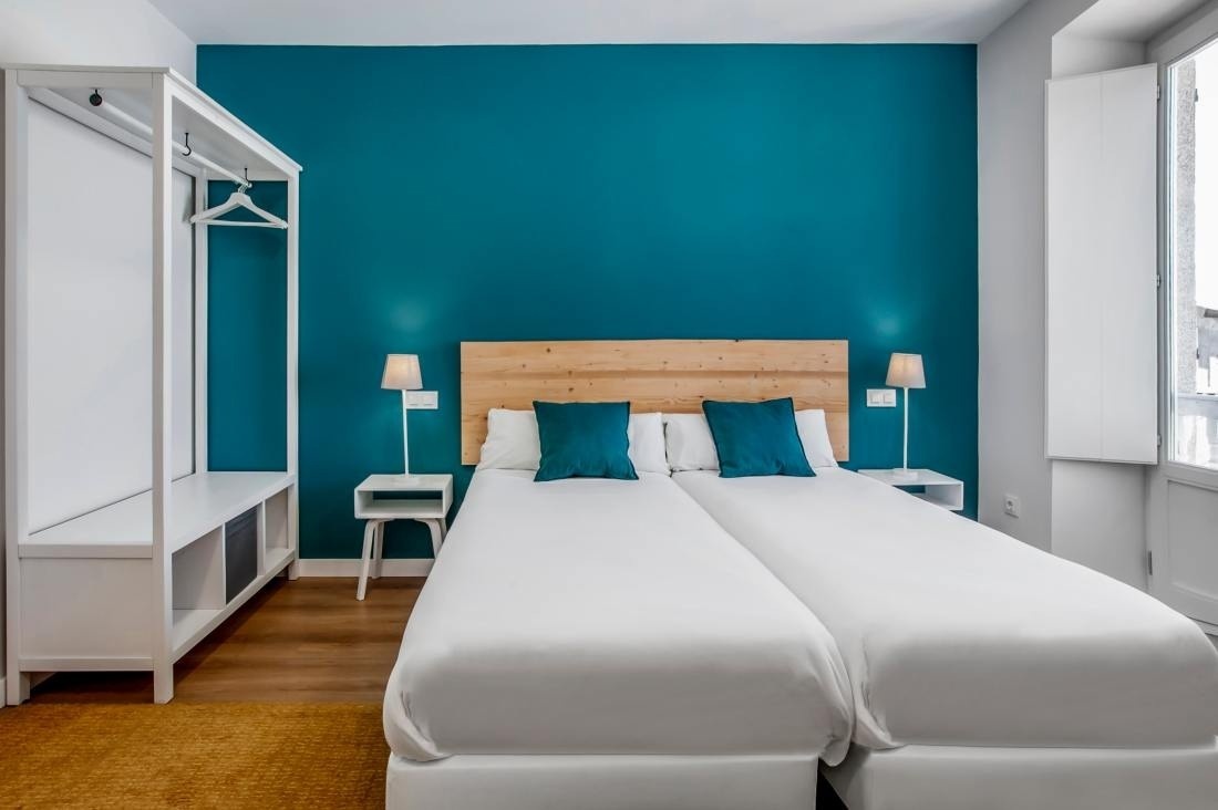 una habitación con dos camas y una pared azul