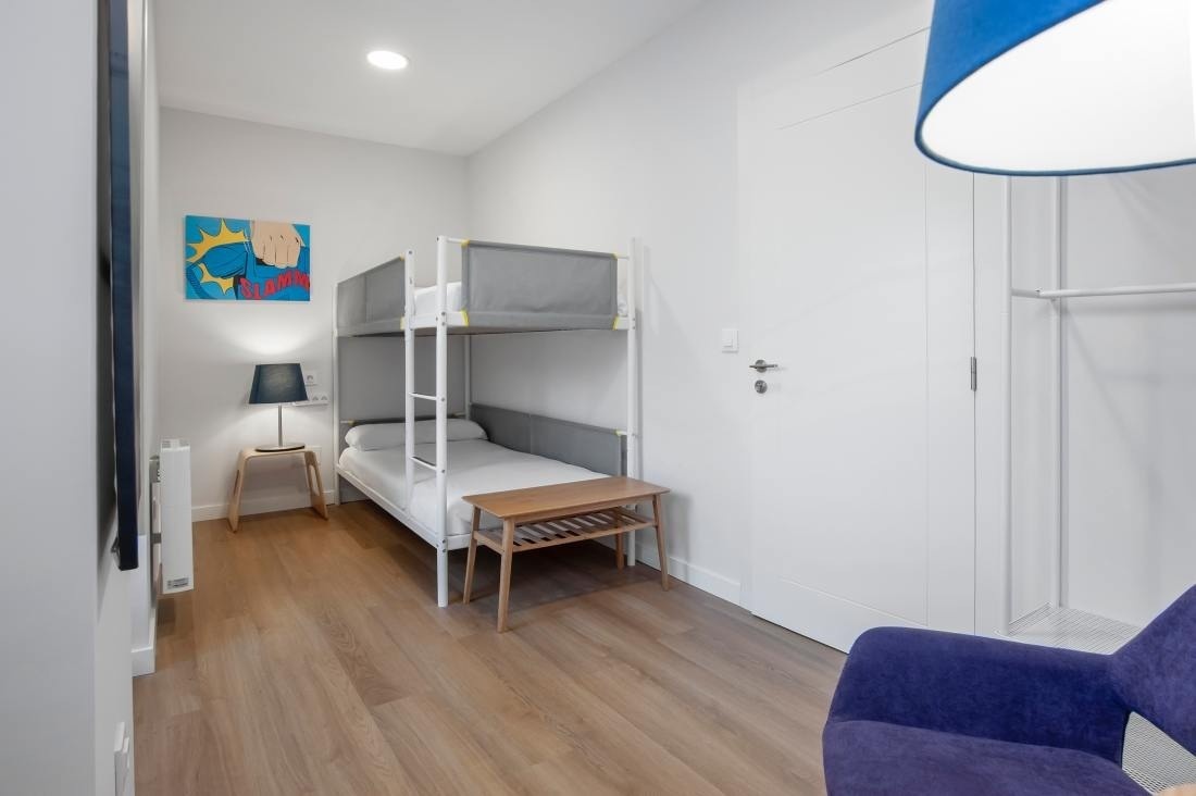 una habitación con dos literas y una pintura de un superhéroe en la pared