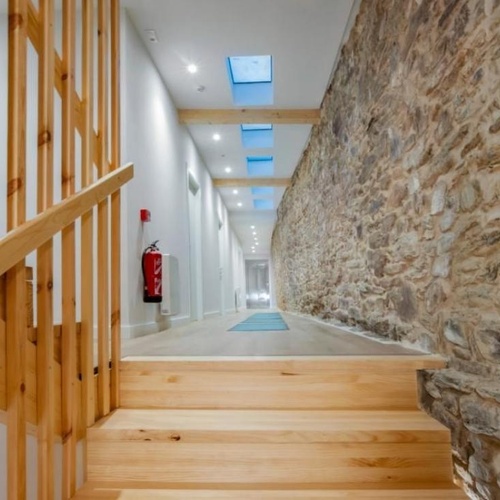 un pasillo con escaleras de madera y una pared de piedra