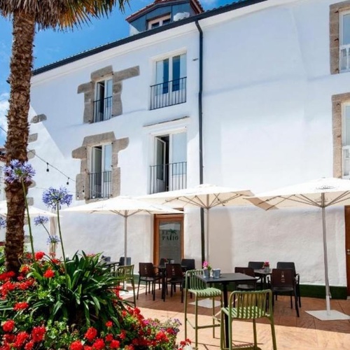 un patio con mesas y sillas y paraguas frente a una casa blanca