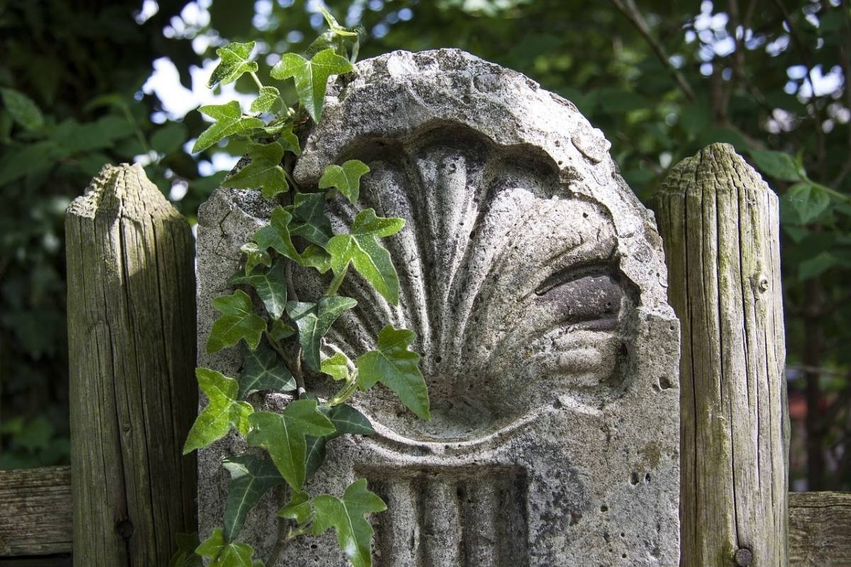 una escultura de piedra con hojas verdes sobre una cerca de madera