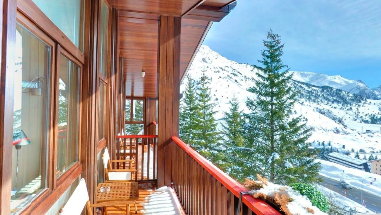 un balcón de madera con vistas a las montañas cubiertas de nieve