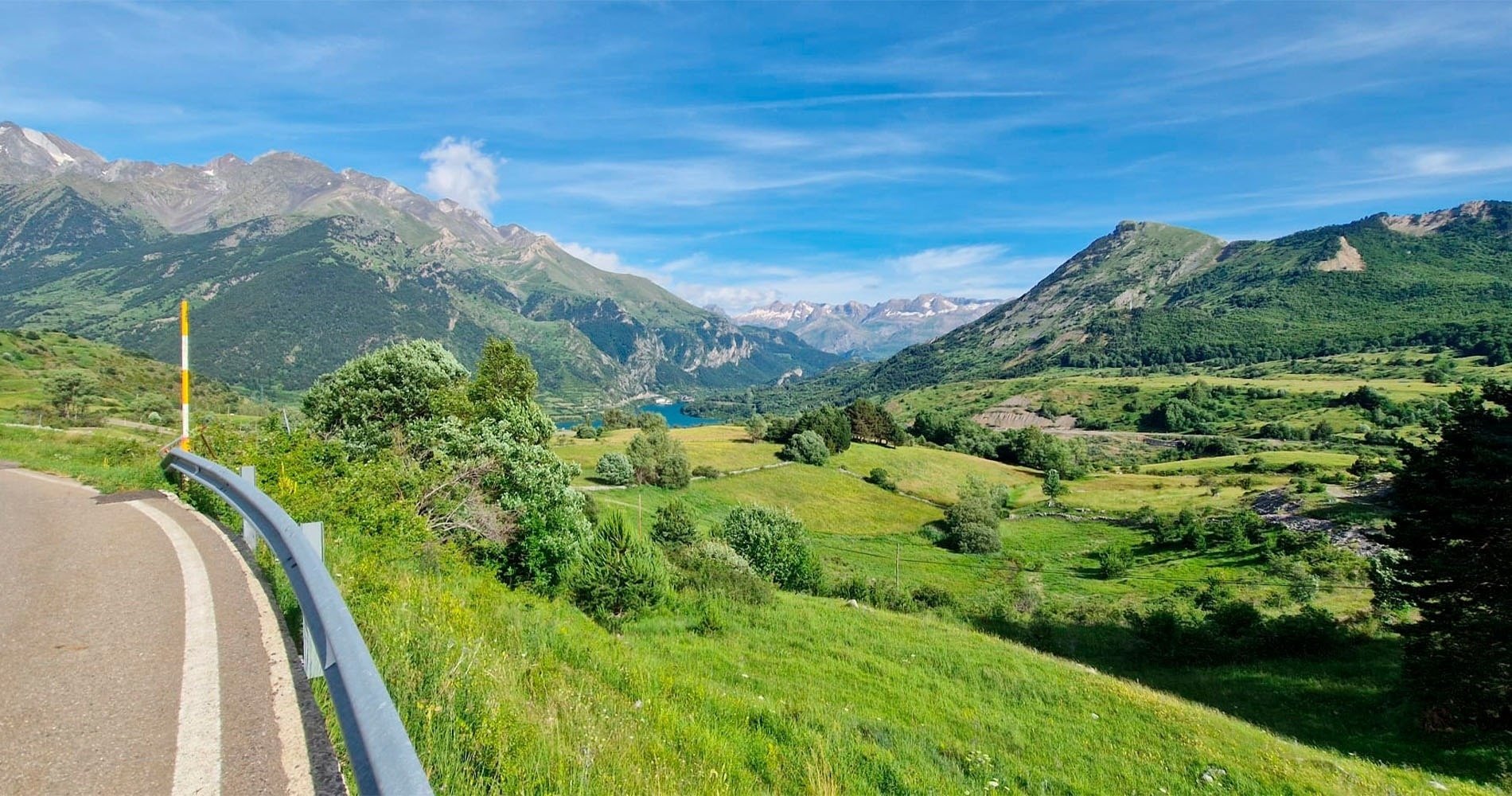 a church in the mountains with pink flowers in the foreground