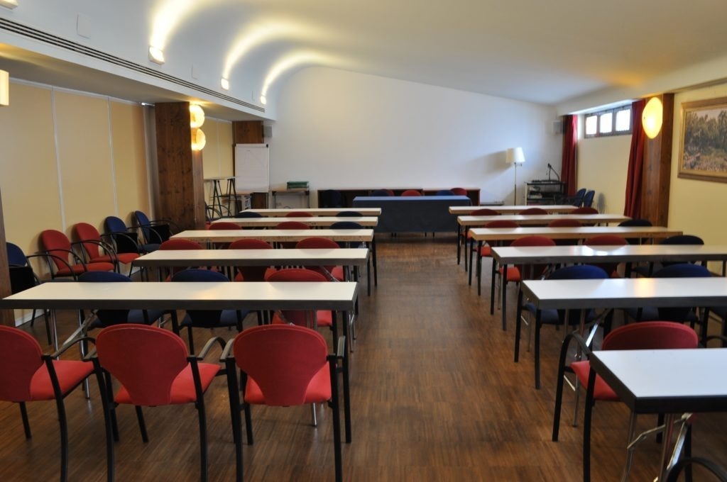 une salle de conférence avec des tables et des chaises rouges et bleues