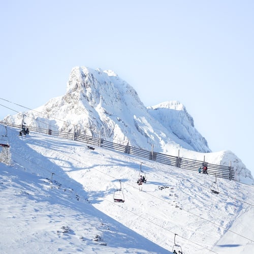 una montaña cubierta de nieve con un teleférico en primer plano